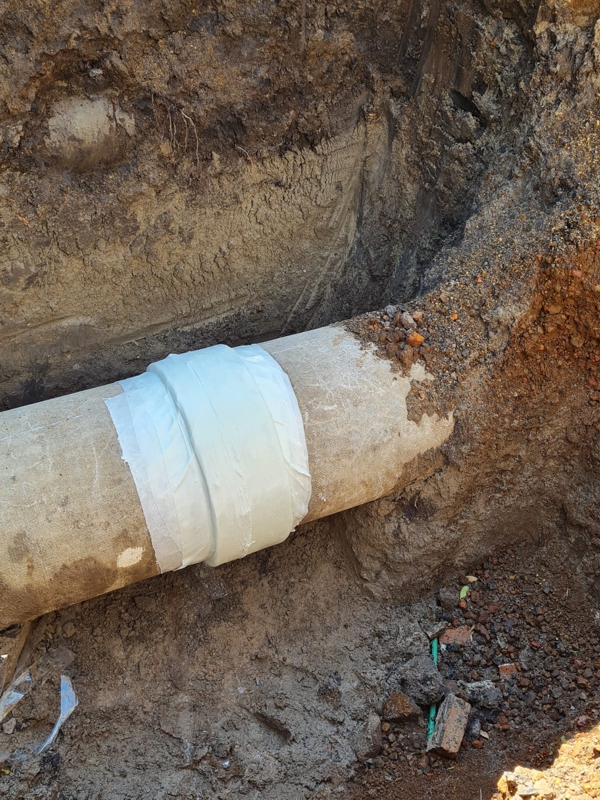 Asbestos cement pipe leaking from a sleeve is repaired using a SylWrap HD Pipe Repair Bandage