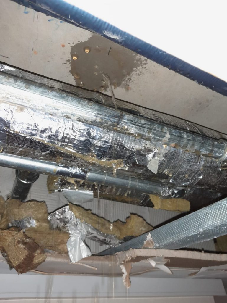 A leaking steel pipe in ceiling cavity part of a district heating system before undergoing repair using a SylWrap Pipe Repair Contractor Case